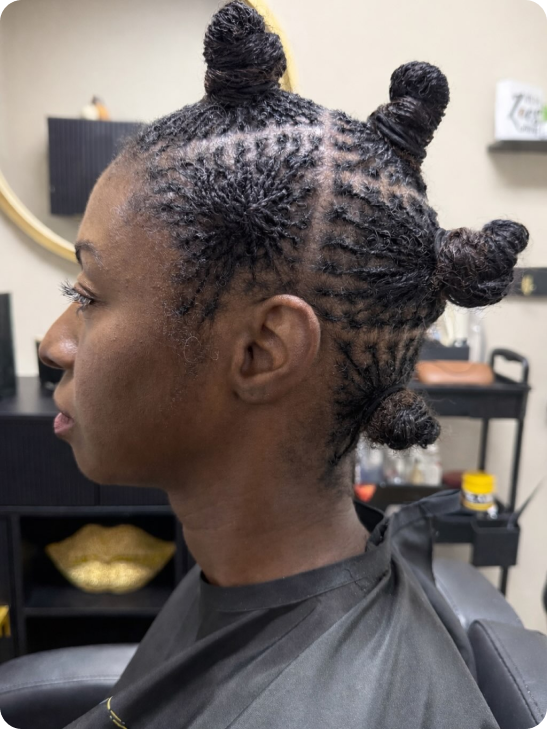 Woman with intricate twisted bantu knot hairstyle in a salon.