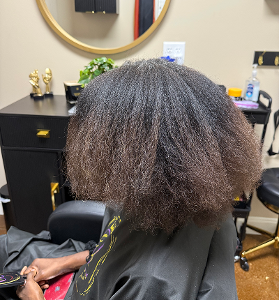 Person with natural, textured hair sitting in a salon chair.