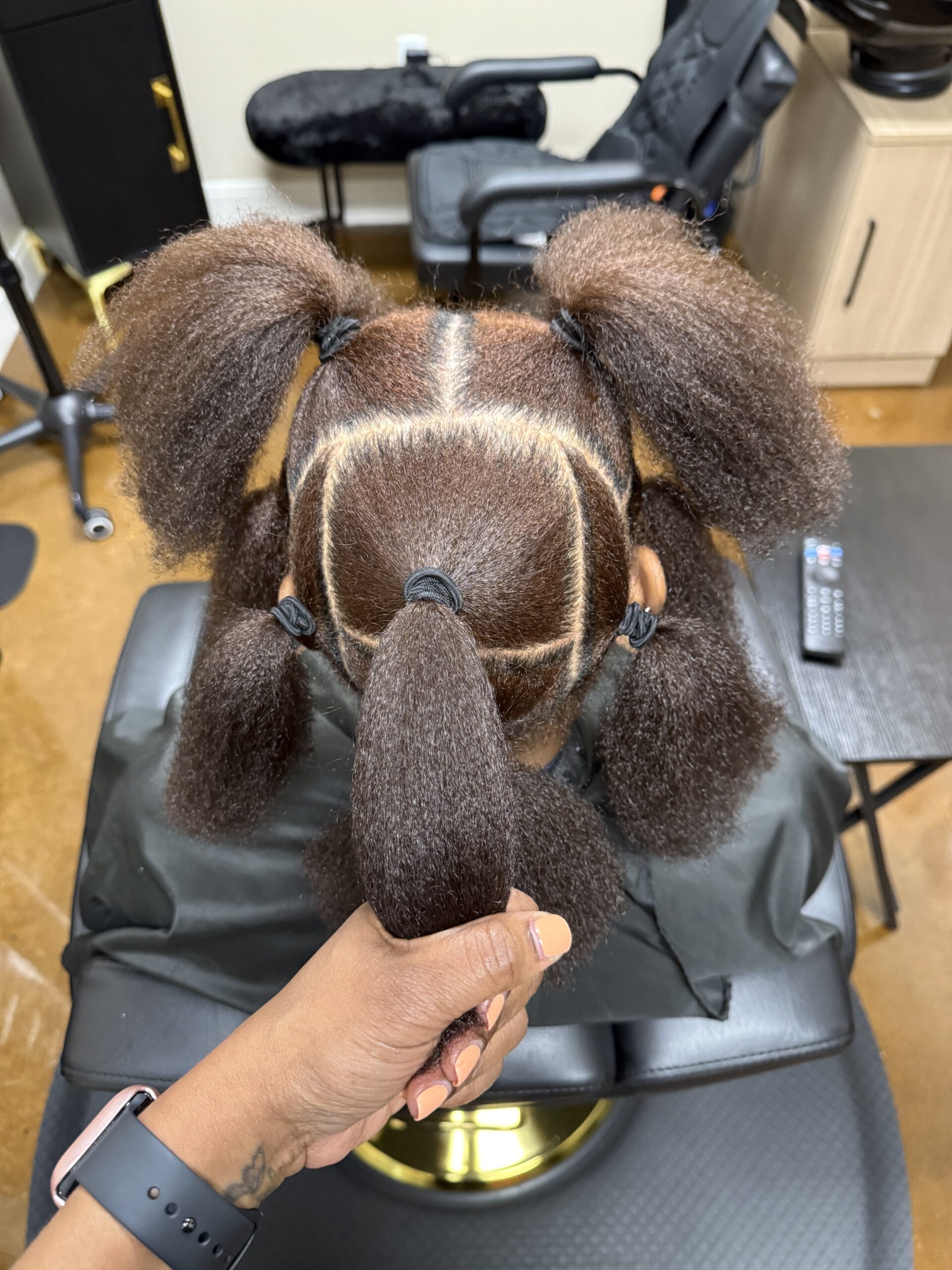 Intricate puffy hairstyle with geometric parting and ponytails.