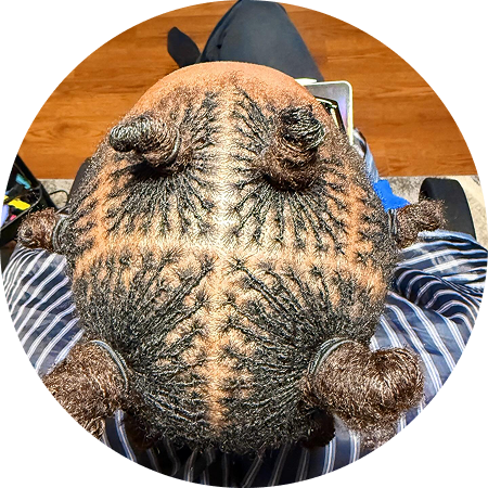 Intricate geometric hair tattoo on a shaved head with small buns.